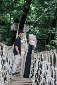 Young couple standing on footbridge at forest