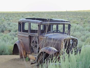 Old abandoned car on field