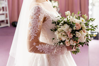 Midsection of bride holding bouquet