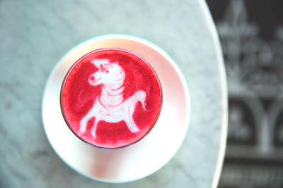 Beetroot latte on marble background with unicorn art on the top. flat lay view. color trendy latte.