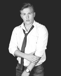 Portrait of young man standing against black background