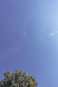 Low angle view of airplane flying against clear blue sky