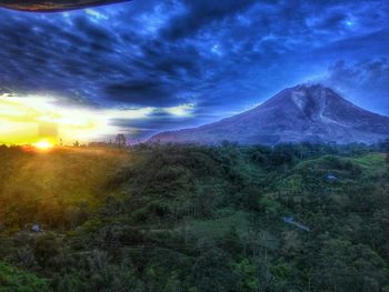 Scenic view of landscape against cloudy sky during sunset