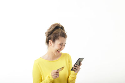 Mid adult man using smart phone against white background