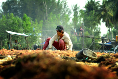 Full length of young man sitting on land