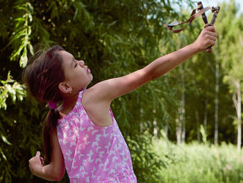 Full length of woman holding plant against trees