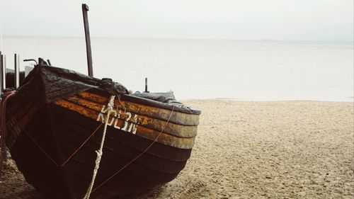 Boat moored on beach against sky