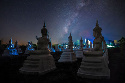 Statues against sky at night