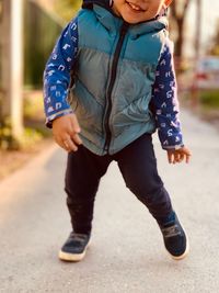 Low section of boy walking on footpath