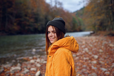 Young woman standing by tree during autumn