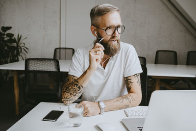 Businessman talking through earphones while working in coworking office