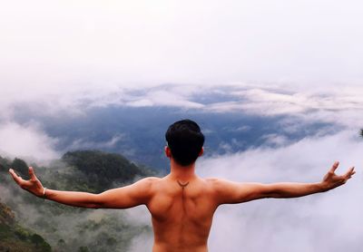 Rear view of shirtless man standing against sky