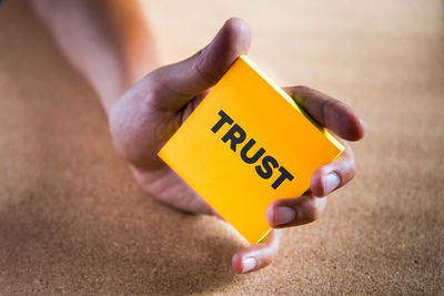 Close-up of person hand holding yellow text