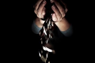 Cropped image of woman covering face against black background