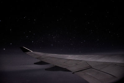 Airplane wing against sky at night