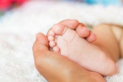 Cropped hand of woman holding baby foot at home