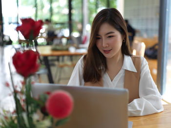 Smiling young businesswoman using laptop while sitting at cafe