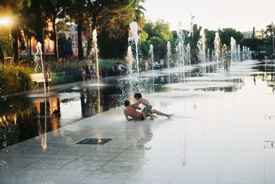 People on wet lake against trees