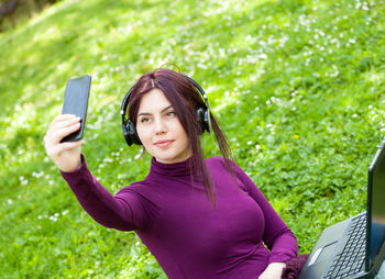 Portrait of young woman photographing through smart phone