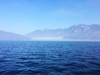 Scenic view of sea and mountains against clear blue sky