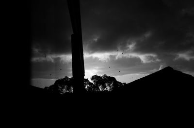 Low angle view of silhouette trees against storm clouds
