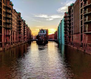 Canal amidst buildings in city against sky