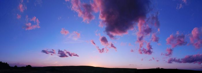 Low angle view of silhouette landscape against blue sky