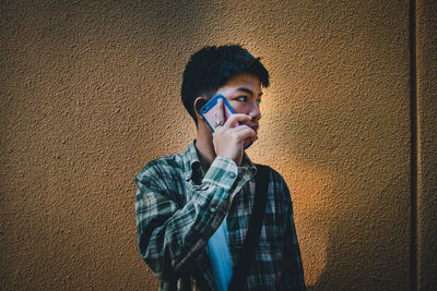 Portrait of young man standing against wall