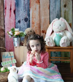 Portrait of cute girl with toy sitting outdoors