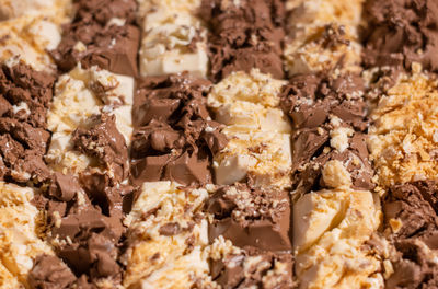 White and brown chocolate prepared for a broken chocolate topped with pretzel, sugar pearls and nuts