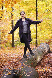 Portrait of smiling young woman with autumn leaves on tree