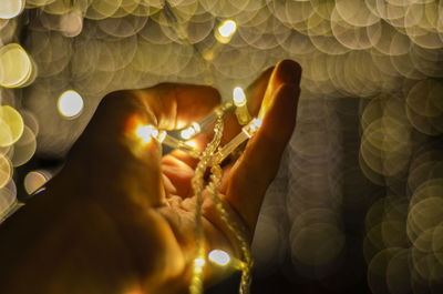 Close-up of hand holding lit candles