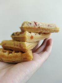 Close-up of hand holding burger against white background