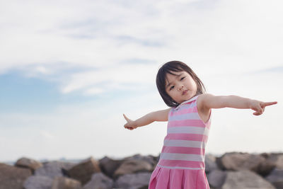 Girl standing on rock against sky