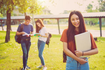 Friends studying while standing at park