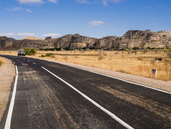 Road leading towards mountains against sky