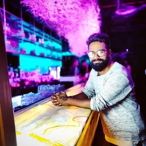 Portrait of man standing at counter in illuminated club