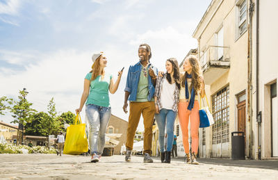 People with shopping bags walking on footpath against sky