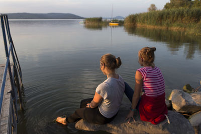 Rear view of people sitting by lake