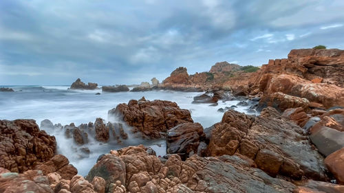 Scenic view of rocks on beach against sky