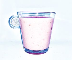 Close-up of drink served on glass against white background