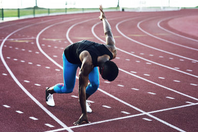 Determined sportsman at starting block on running tracks