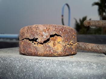 Close-up of rusty damaged metal on rock against sky