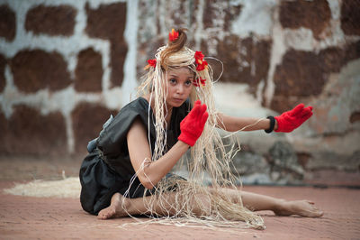 Portrait of girl sitting against wall