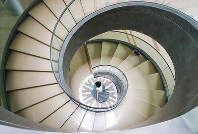 High angle view of woman standing amidst spiral staircases in modern building 