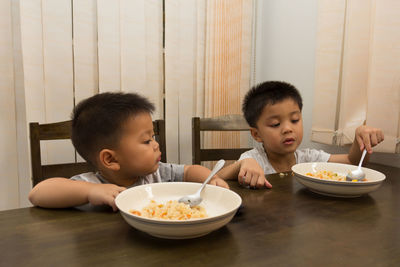 Brothers having food on table at home
