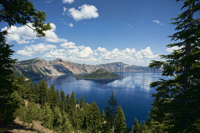 Scenic view of lake by trees against blue sky