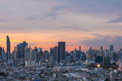 Modern buildings in city against sky during sunset