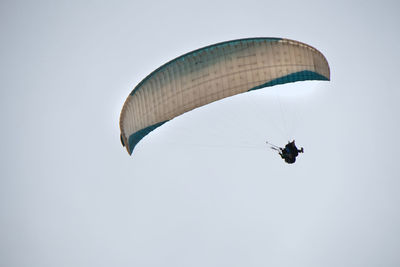 Low angle view of person paragliding against clear sky