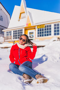 Portrait of smiling young woman sitting on snow